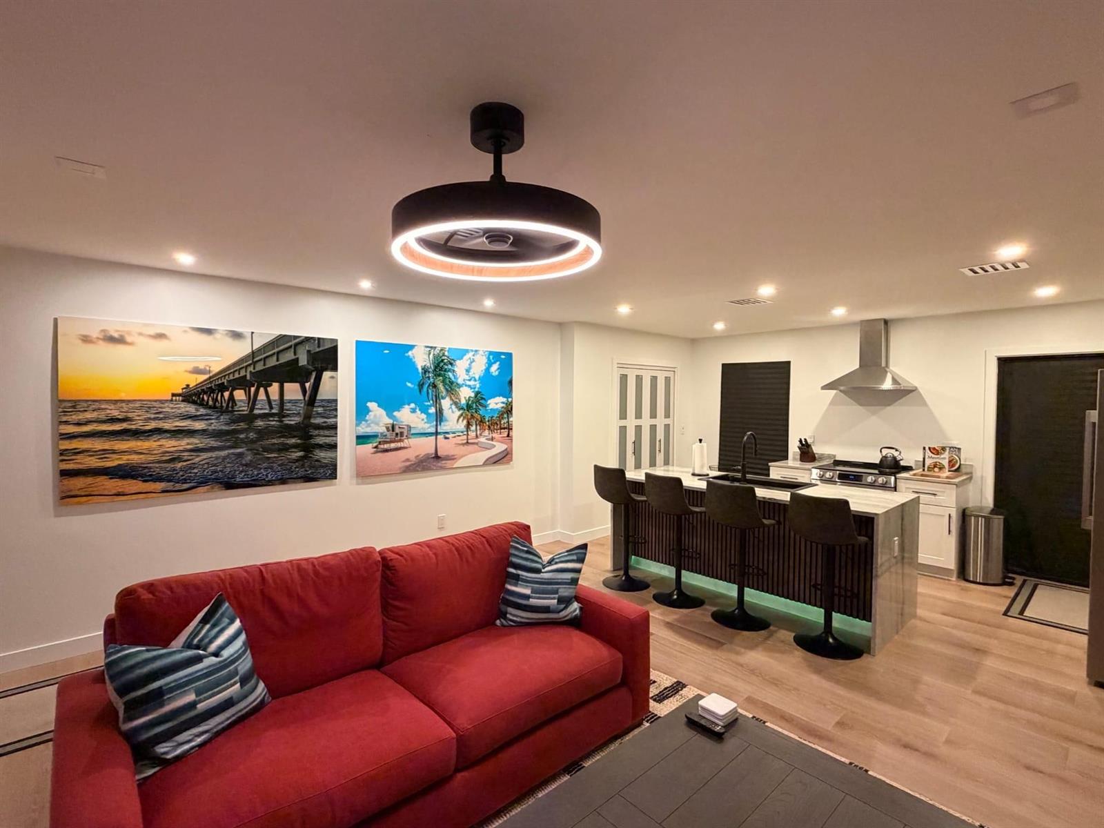 A living room with a red sofa, a kitchen island with barstools, and ceiling lighting — 1025 NW 148th Street, Miami FL 33168, MIAMI, FL
