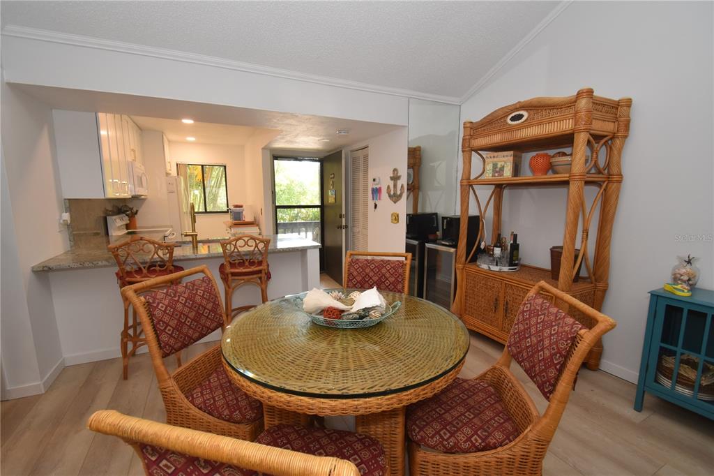 A dining area with a glass-topped wicker table and chairs, adjacent to a kitchen counter — 1720 GLENHOUSE DRIVE UNIT GL429, SARASOTA, FL
