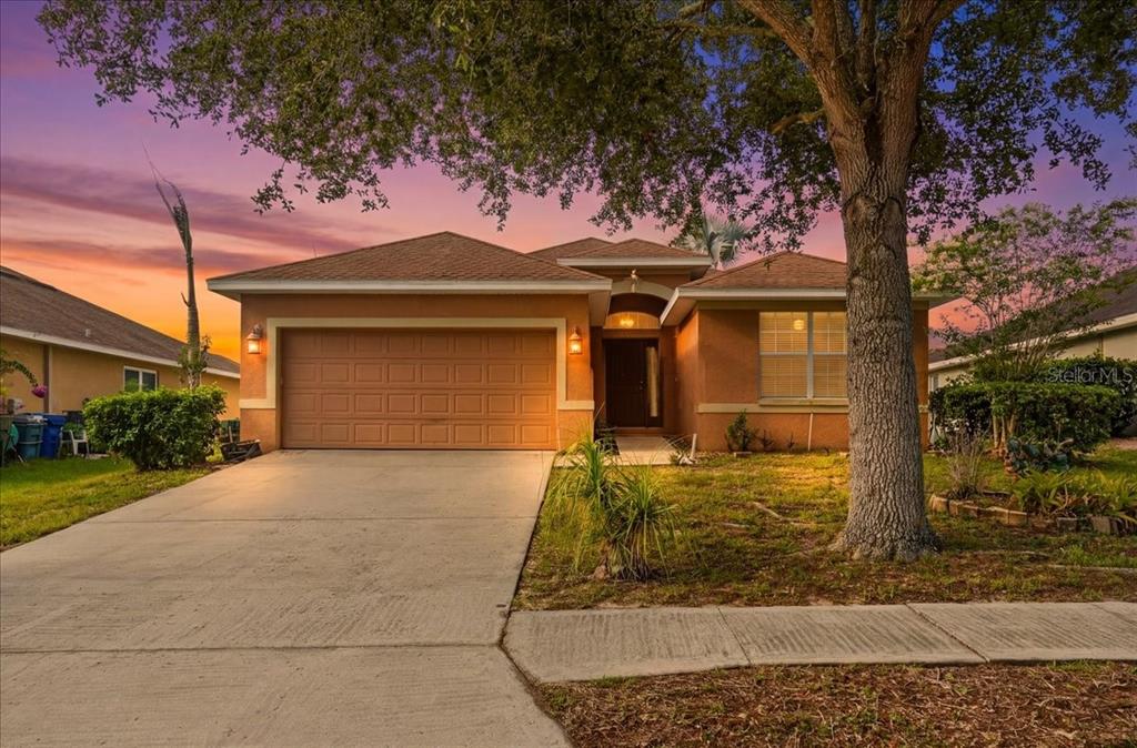 A single-story suburban house with a two-car garage and a large tree in the yard — 1966 WHITE HAWK WAY, WINTER HAVEN, FL