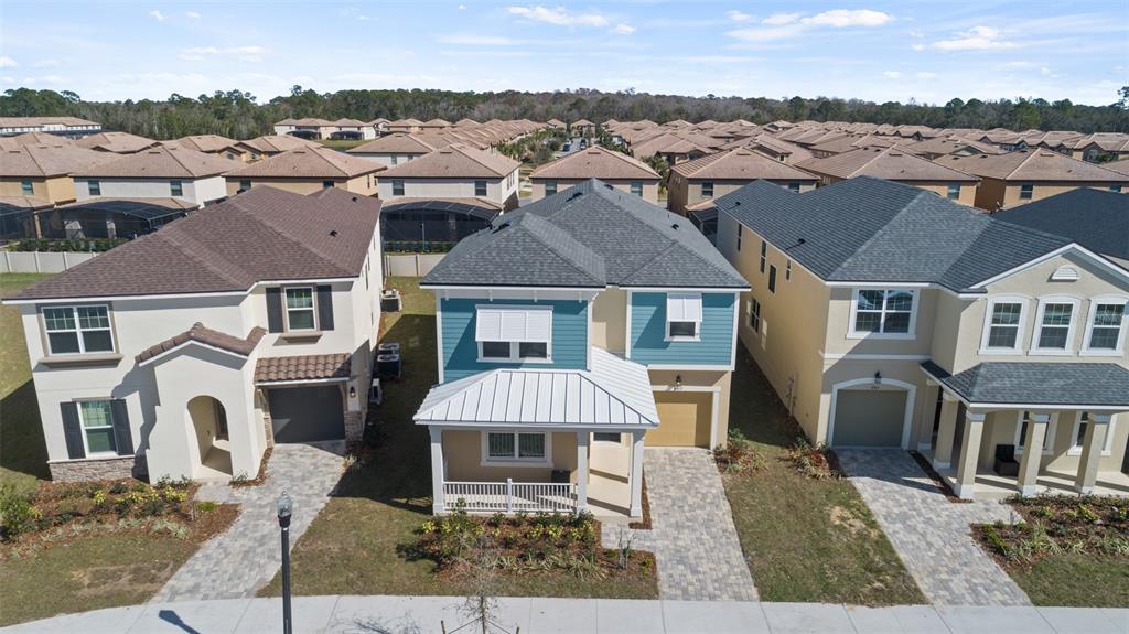 An aerial view shows three suburban houses with paved driveways and shingled roofs — 8917 COCONUT BREEZE DRIVE, KISSIMMEE, FL