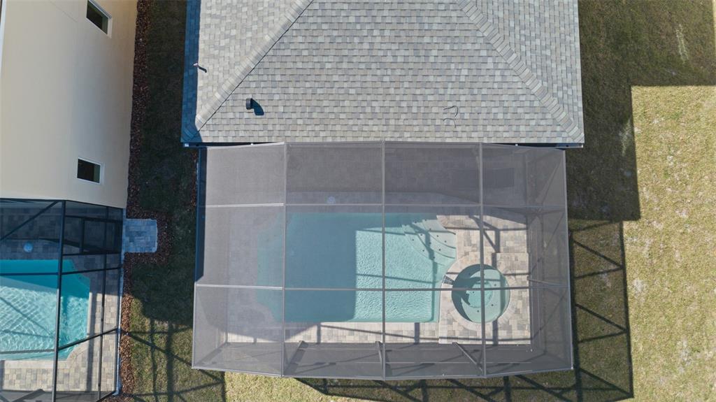 An aerial view shows a house with a screened-in pool and spa in the backyard — 8917 COCONUT BREEZE DRIVE, KISSIMMEE, FL
