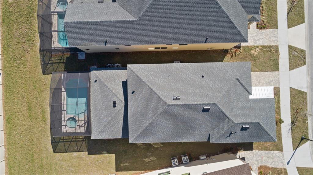 An aerial view shows a house with a shingled roof and a screened-in swimming pool — 8917 COCONUT BREEZE DRIVE, KISSIMMEE, FL