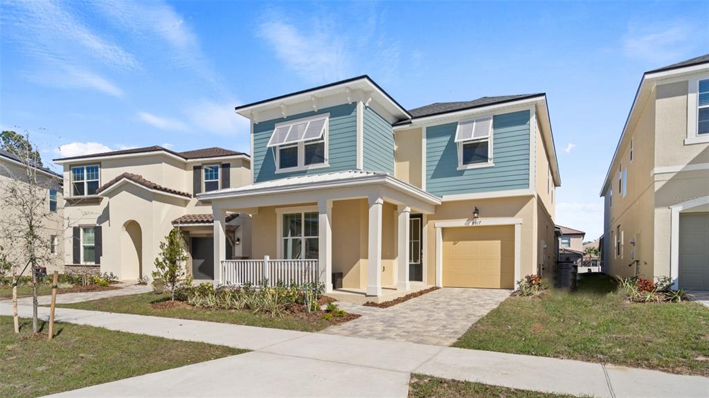 A two-story house with blue siding, a front porch, and a tan garage — 8917 COCONUT BREEZE DRIVE, KISSIMMEE, FL