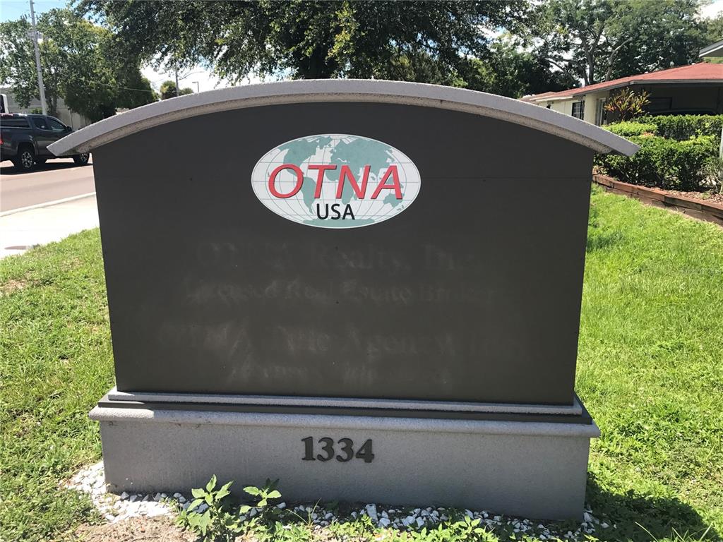 A dark gray monument sign with the OTNA USA logo stands on a grassy lawn — 1334 S SEMORAN BOULEVARD, ORLANDO, FL