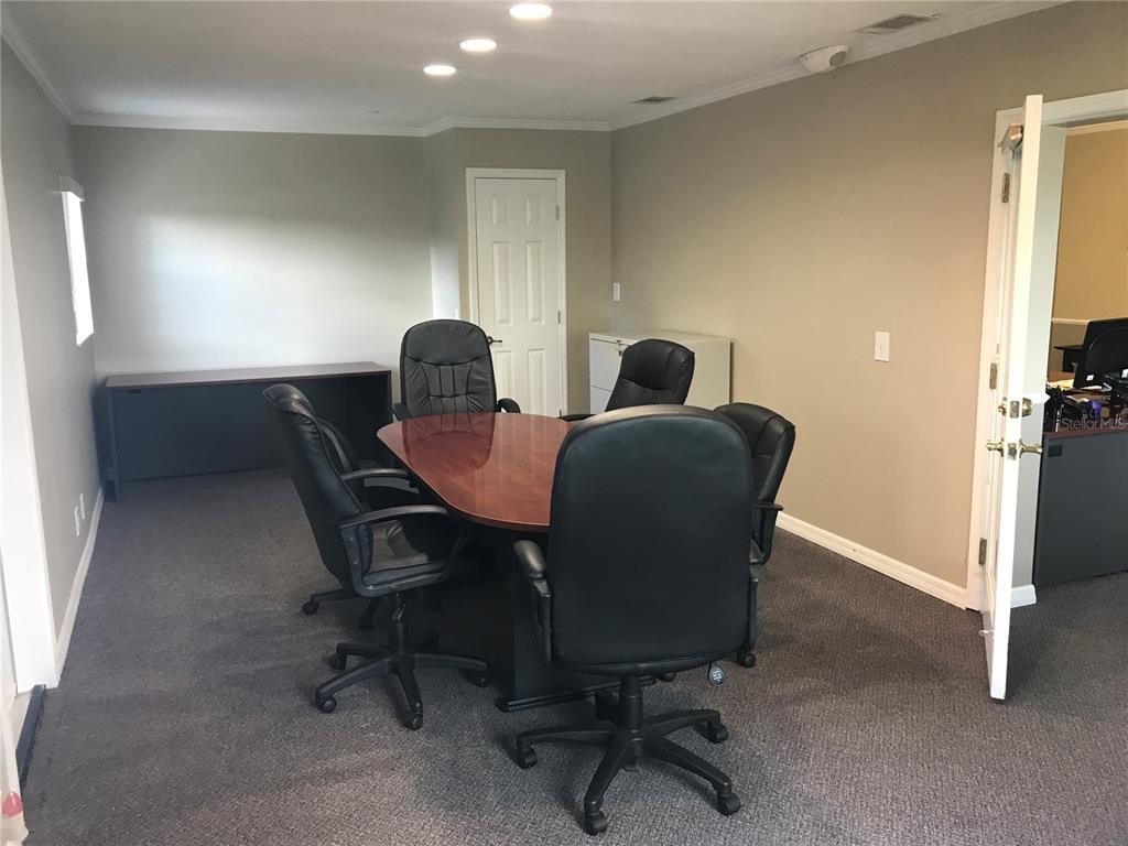 A conference room features a wooden table, five black office chairs, and gray carpeting — 1334 S SEMORAN BOULEVARD, ORLANDO, FL