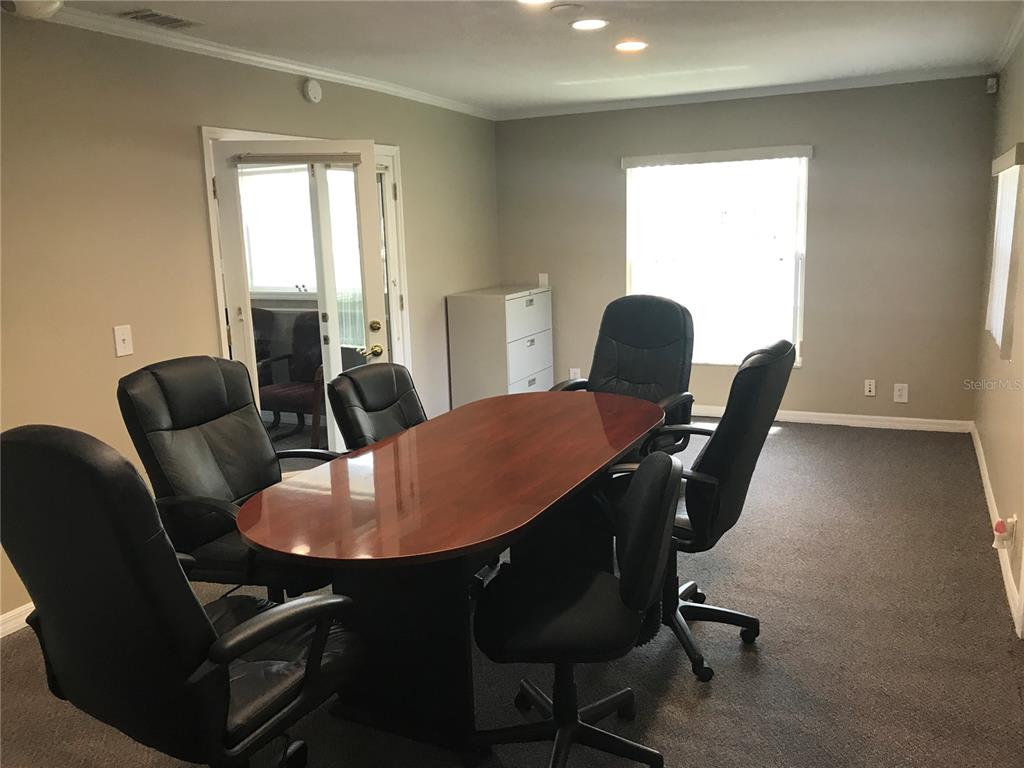 A conference room features a wooden oval table, six black chairs, and gray carpeting — 1334 S SEMORAN BOULEVARD, ORLANDO, FL