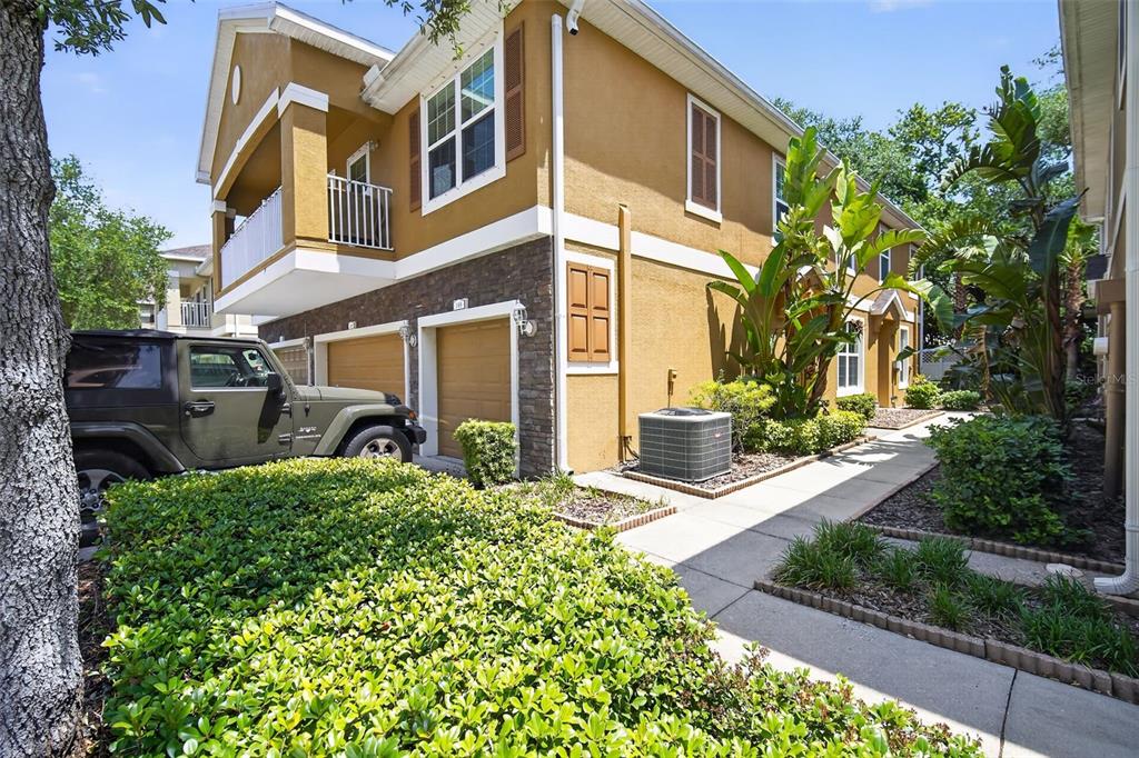 A two-story tan building with a stone facade, garage doors, and a parked green Jeep — 7001 INTERBAY BOULEVARD UNIT 148, TAMPA, FL