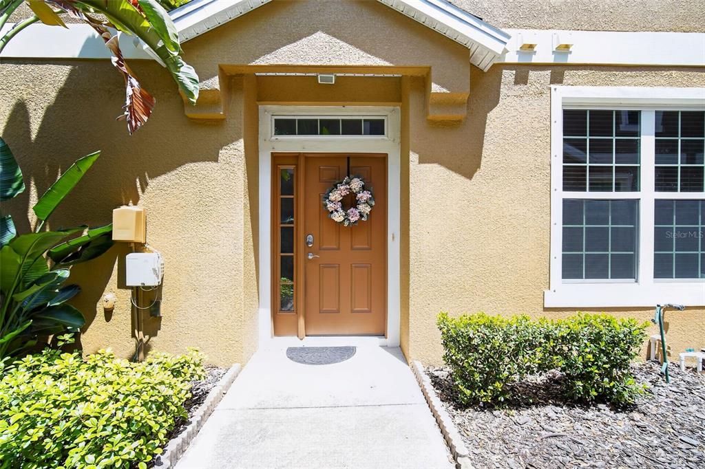 A tan house exterior features a brown front door with a wreath and side window — 7001 INTERBAY BOULEVARD UNIT 148, TAMPA, FL
