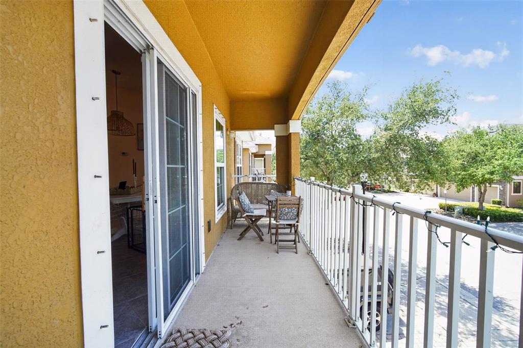 A covered balcony features a sliding glass door, white metal railings, and outdoor patio furniture — 7001 INTERBAY BOULEVARD UNIT 148, TAMPA, FL