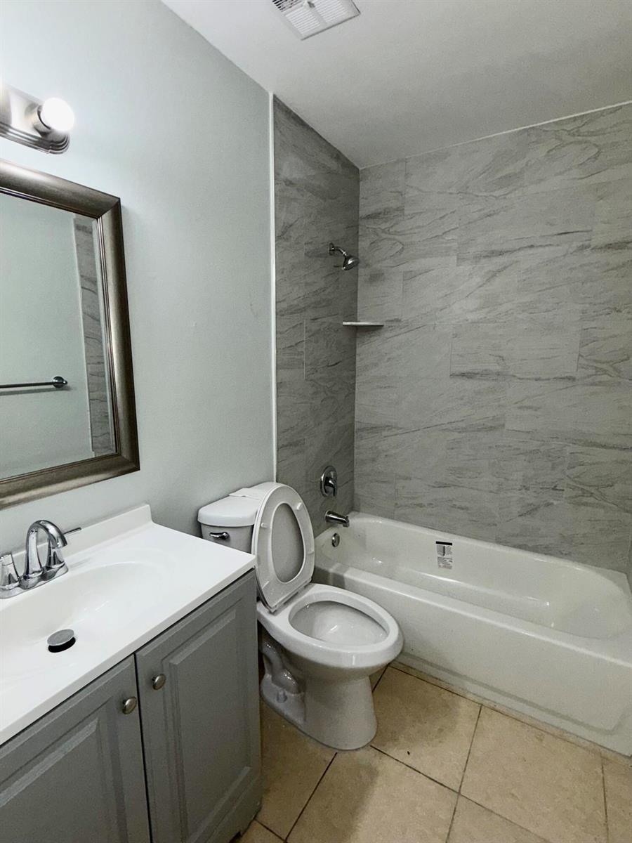 A bathroom features a gray vanity, a toilet, and a bathtub with gray tiled walls — 9392 Affirmed Lane, Boca Raton FL 33496, BOCA RATON, FL