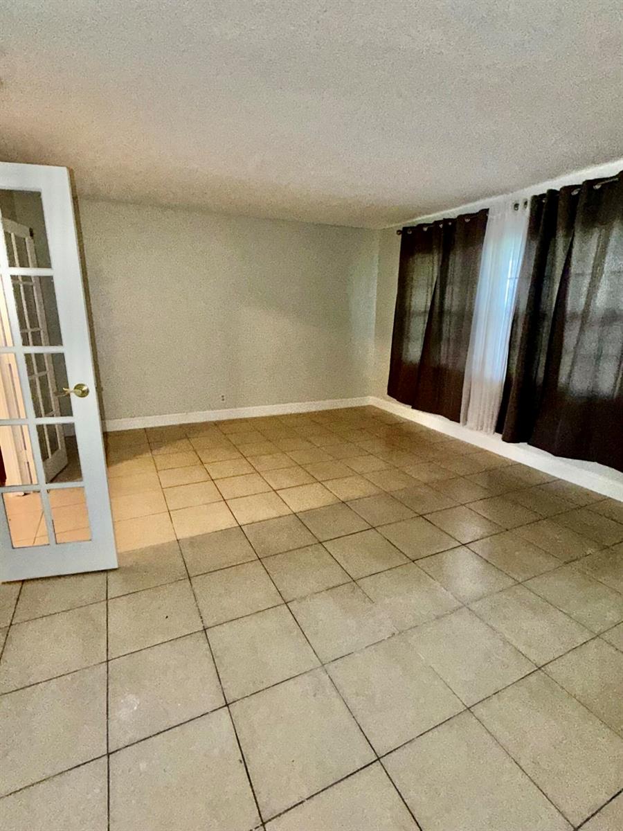 An empty room with light-colored tile flooring, white walls, and dark curtains over windows — 9392 Affirmed Lane, Boca Raton FL 33496, BOCA RATON, FL