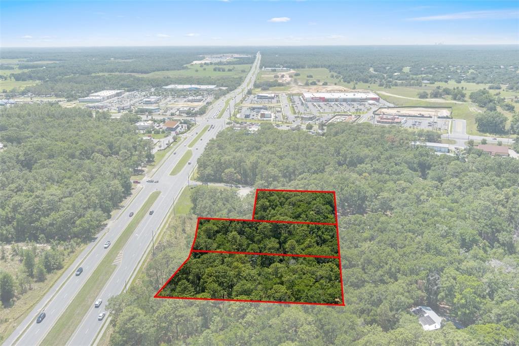 An aerial view shows a wooded plot of land outlined in red beside a highway — 2767 W NORVELL BRYANT HIGHWAY, LECANTO, FL