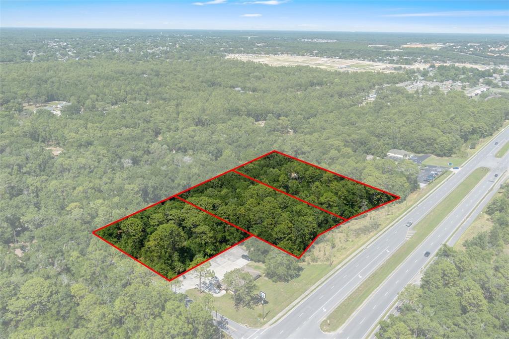 An aerial view shows a wooded plot of land outlined in red near a highway — 2767 W NORVELL BRYANT HIGHWAY, LECANTO, FL
