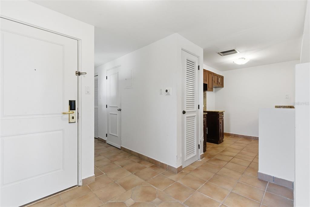 An entryway with tile flooring leads to a kitchen featuring dark wood cabinets — Las Casitas I 1000 AVENUE EL CONQUISTADOR UNIT 5241-42-43, FAJARDO, PR