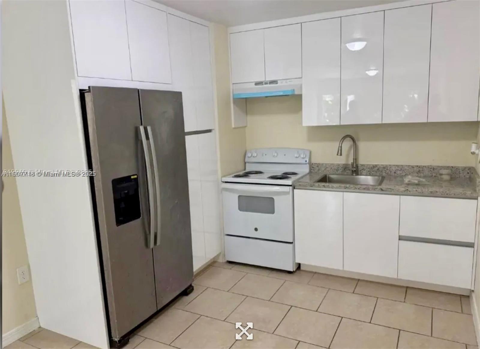 A kitchen features white cabinets, a stainless steel refrigerator, a white stove, and tile flooring — 22210 SW 116th Ave # D, Miami FL 33170, MIAMI, FL