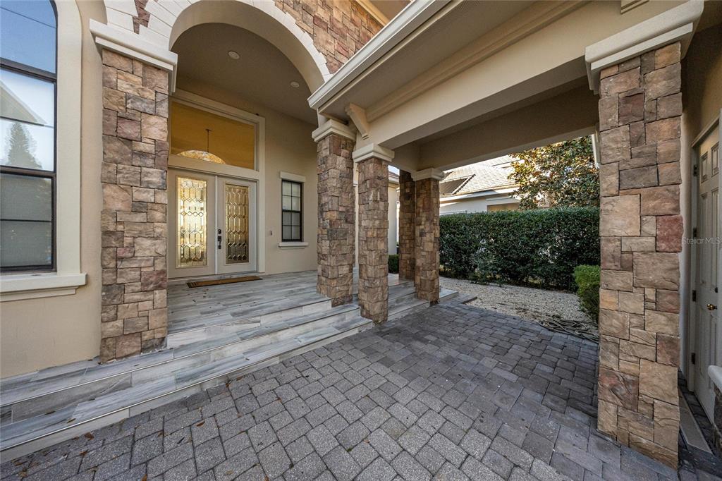 The exterior entrance features stone-clad pillars, a paved walkway, and a glass-paneled double front door — 2730 NW 80TH AVENUE, OCALA, FL