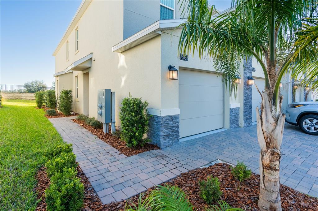 A beige two-story townhouse exterior features a single-car garage, stone accents, and a paver walkway — 581 OCEAN COURSE AVENUE UNIT 581, DAVENPORT, FL