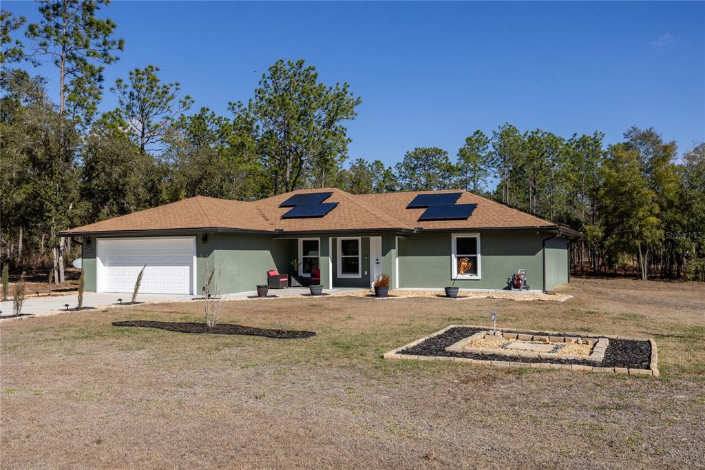 A single-story house with a green exterior, a two-car garage, and solar panels on the roof — 5793 SW 121ST TERRACE, OCALA, FL