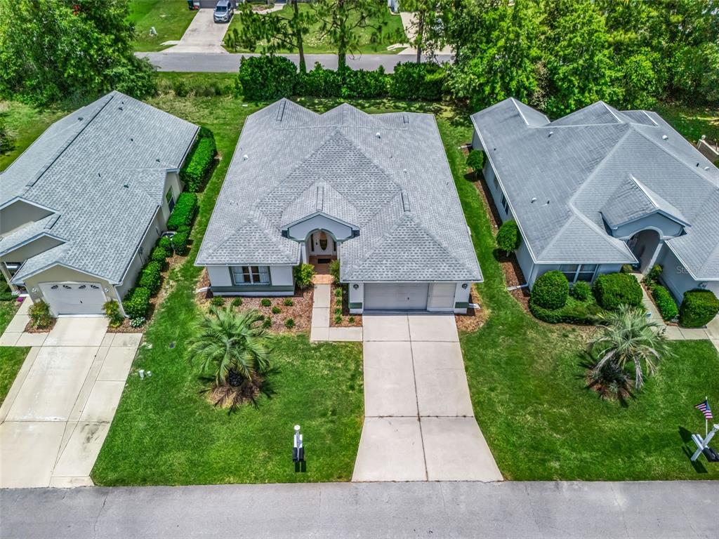 An aerial view shows three suburban houses with gray shingled roofs and concrete driveways — 6318 SW 117TH LOOP, OCALA, FL
