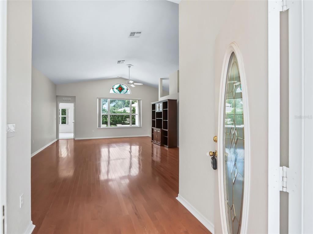An entryway opens into a living room with hardwood floors, vaulted ceilings, and a window — 6318 SW 117TH LOOP, OCALA, FL