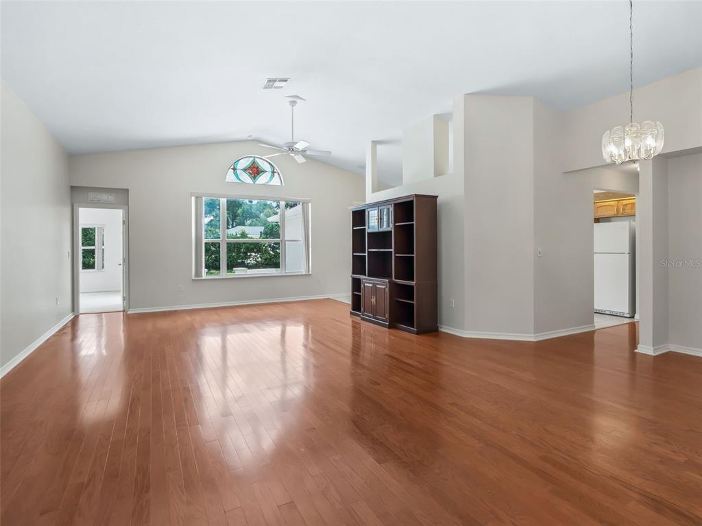 A spacious living room features hardwood floors, a vaulted ceiling, and a large arched window — 6318 SW 117TH LOOP, OCALA, FL