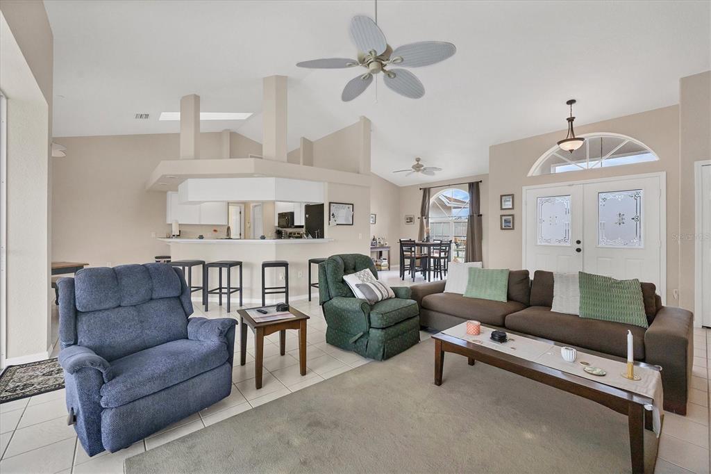 A living room with tile floors, a ceiling fan, and an open kitchen with bar seating — 102 MARKER ROAD, ROTONDA WEST, FL