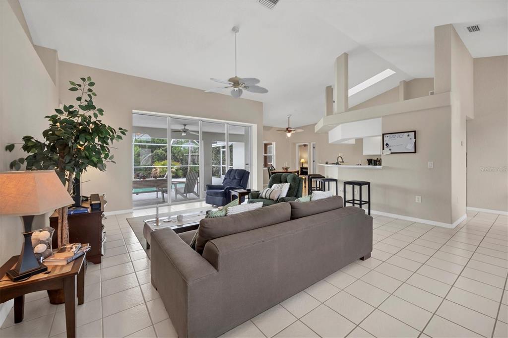 A living room with tile floors, a gray sofa, and a sliding door to a patio — 102 MARKER ROAD, ROTONDA WEST, FL