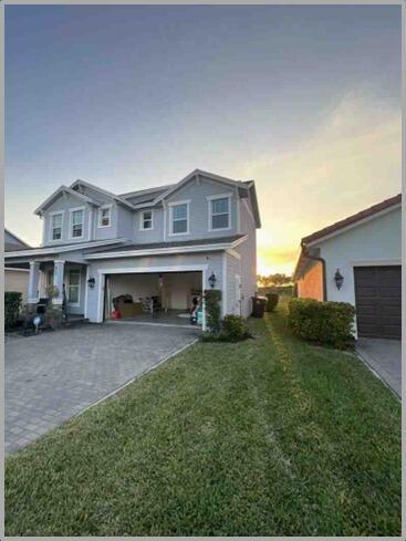 A two-story house with a light blue exterior, an open garage, and a paved driveway — 857 Wandering Willow Way, FL 33470, FL