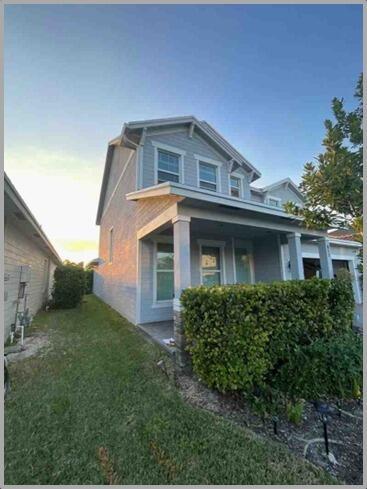 A two-story house with light blue siding, a front porch, and a manicured hedge — 857 Wandering Willow Way, FL 33470, FL