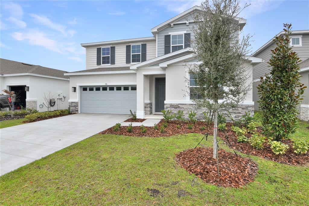 A two-story suburban house with a gray garage, stone accents, and a front lawn — 176 BLUE STAR COURT, TAVARES, FL
