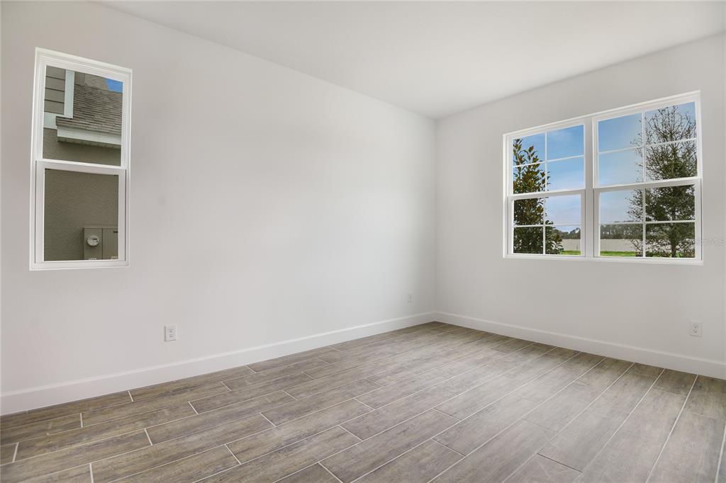 An empty room with white walls, gray wood-look tile flooring, and two windows — 176 BLUE STAR COURT, TAVARES, FL