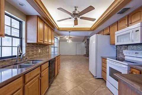 A kitchen with wood cabinets, tile floors, and a ceiling fan opens to a living area — 7528 RIVER COUNTRY DRIVE, WEEKI WACHEE, FL