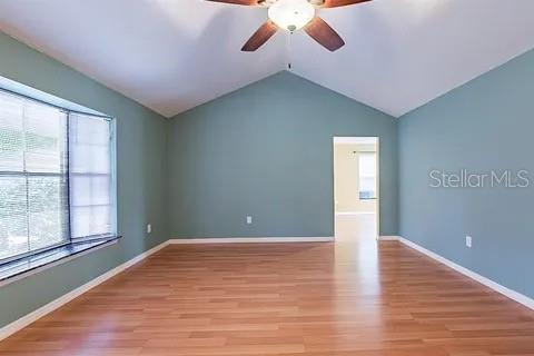 An empty room with light blue walls, wood-look flooring, a vaulted ceiling, and a ceiling fan — 7528 RIVER COUNTRY DRIVE, WEEKI WACHEE, FL