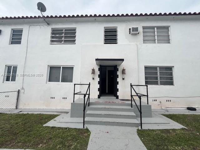 The exterior of a two-story white apartment building features a central entrance with stairs — MIAMI, FL