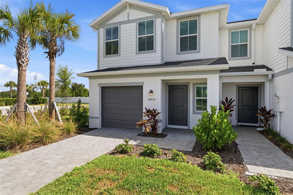 A two-story townhouse with a gray garage door, white siding, and a paved walkway — 14035 LILAC SKY TERRACE, BRADENTON, FL