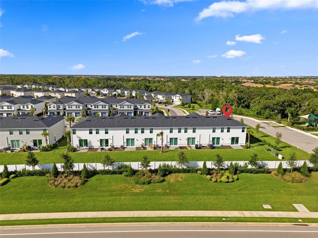 An aerial view shows a row of white townhouses with dark roofs and backyard fences — 14035 LILAC SKY TERRACE, BRADENTON, FL