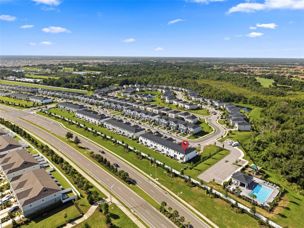 An aerial view shows a residential neighborhood with townhomes, a community pool, and a roadway — 14035 LILAC SKY TERRACE, BRADENTON, FL