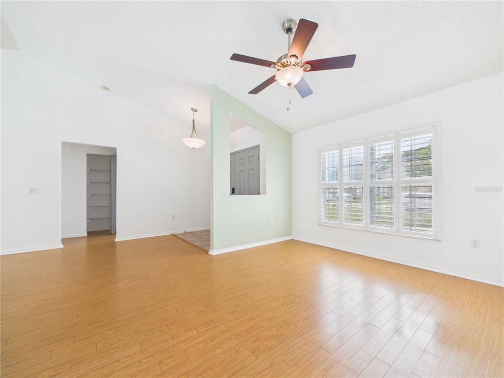 A living room with light wood flooring, a ceiling fan, and a light green accent wall — 9434 HOLNWON COURT, HUDSON, FL