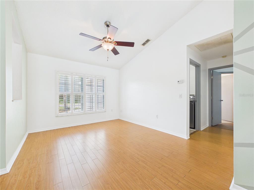 An empty room with light wood flooring, white walls, a ceiling fan, and plantation shutters — 9434 HOLNWON COURT, HUDSON, FL