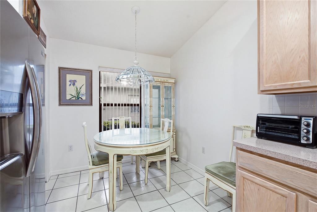 A dining area features a glass-topped table, white chairs, tile flooring, and a hanging light fixture — 9419 GREEN NEEDLE DRIVE, NEW PORT RICHEY, FL