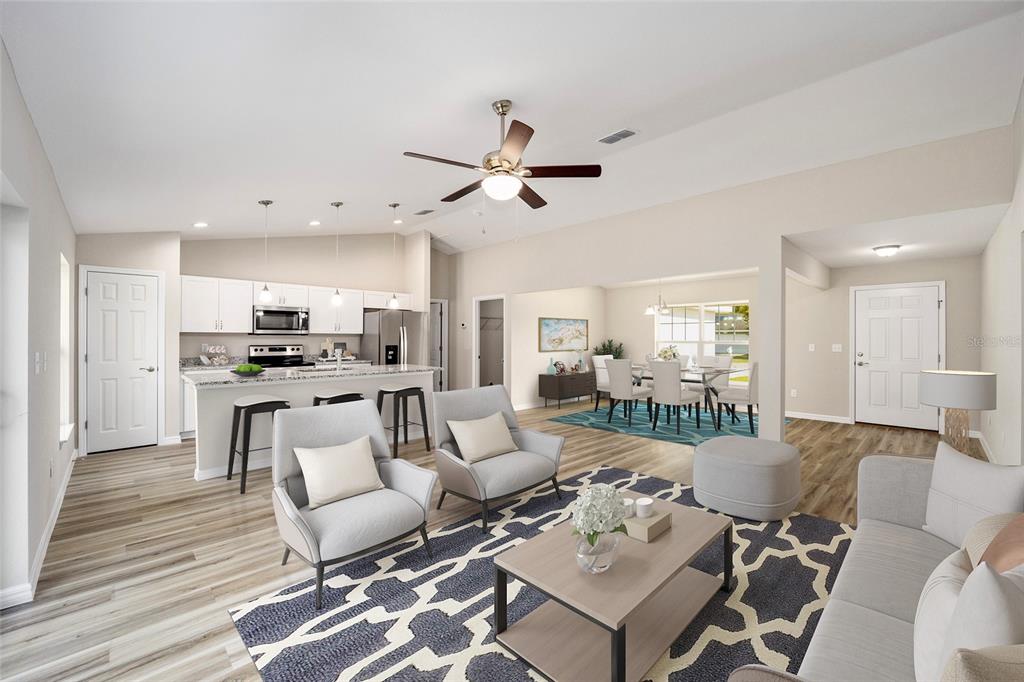 An open-concept living room, kitchen, and dining area with light wood floors and neutral decor — 12995 SW 89TH COURT, OCALA, FL