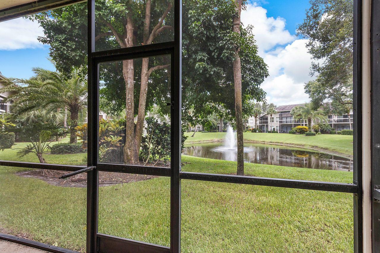A view of a pond with a fountain from a screened-in porch — 11863 Wimbledon Circle # 426, Wellington FL 33414, WELLINGTON, FL