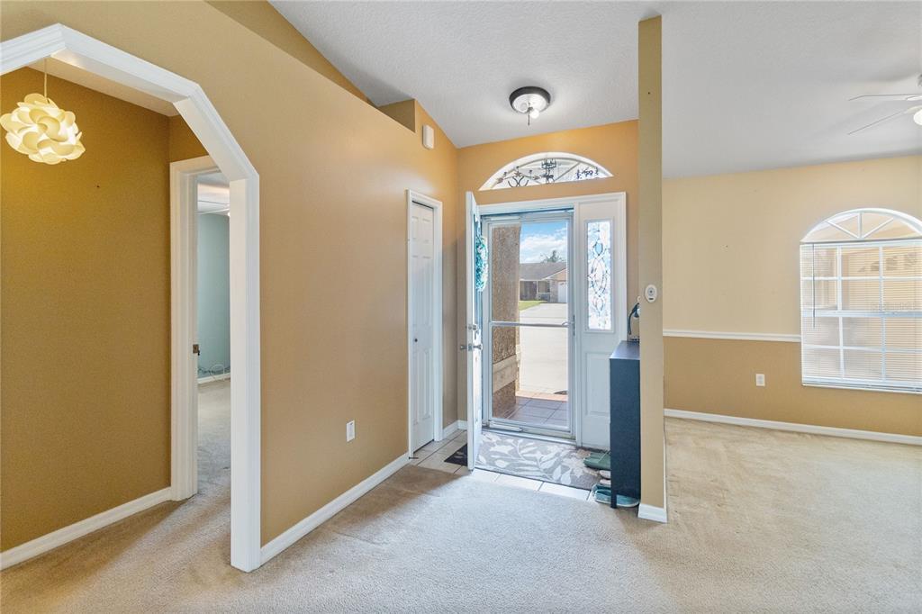 An entryway with beige walls, carpeted flooring, a white front door, and an arched doorway — 2310 GISELLE COURT, ST CLOUD, FL