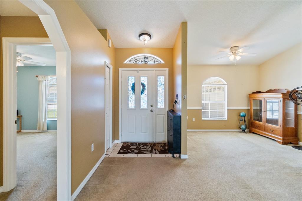 An entryway with a white front door, beige carpet, and an arched doorway to the left — 2310 GISELLE COURT, ST CLOUD, FL