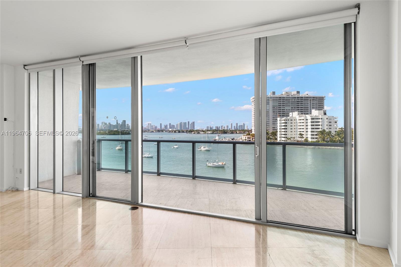 A room with light-colored tile flooring features large sliding glass doors opening to a balcony — 1470 16th St # 501, Miami Beach FL 33139, MIAMI BEACH, FL