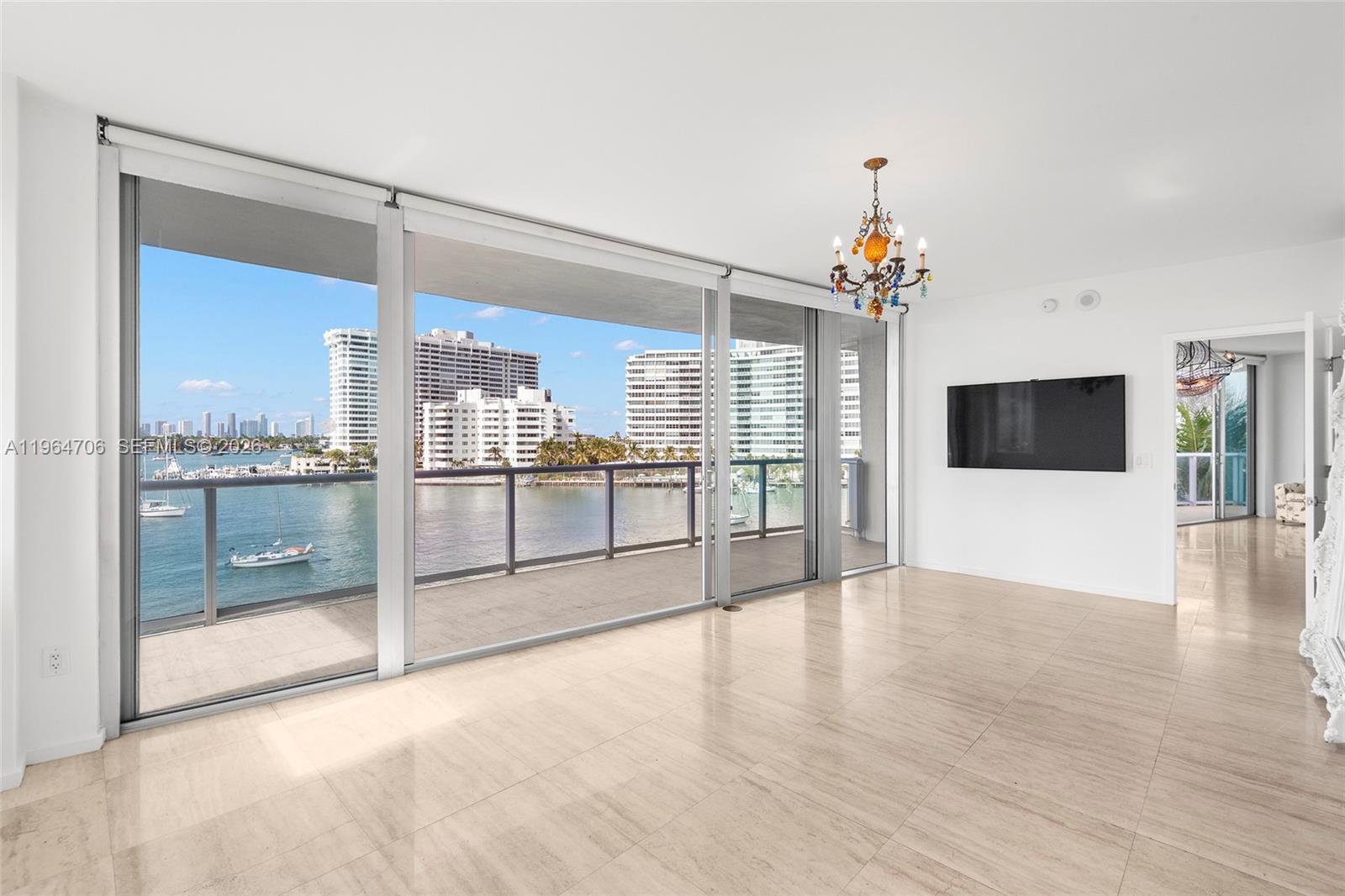 A bright living room features large sliding glass doors, a balcony, and a wall-mounted television — 1470 16th St # 501, Miami Beach FL 33139, MIAMI BEACH, FL