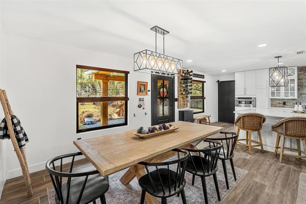 A modern kitchen features a large white island, stainless steel appliances, and wood-look tile flooring — 17224 OLD COUNTRY LANE, WINTER GARDEN, FL