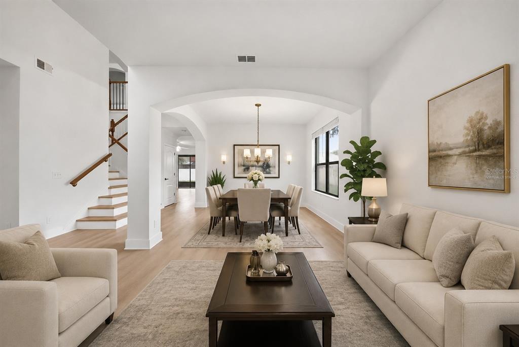 A living room with a sofa and armchair leads to a dining area with arched openings — 1908 ABBEY RIDGE DRIVE, DOVER, FL