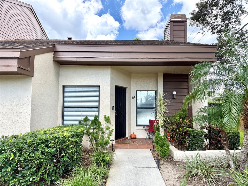 The exterior of a single-story home features a concrete walkway leading to a front entrance — 2816 COUNTRYBROOK DRIVE UNIT L16, PALM HARBOR, FL