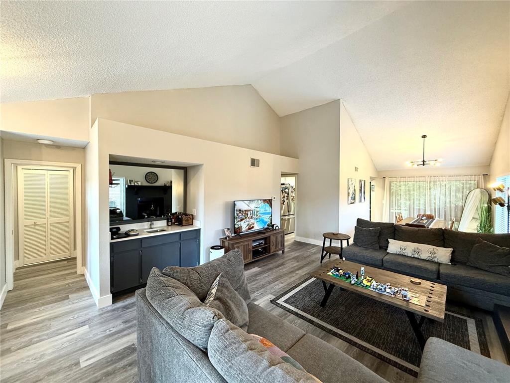 A living room features vaulted ceilings, a wet bar, and gray wood-look flooring — 2816 COUNTRYBROOK DRIVE UNIT L16, PALM HARBOR, FL